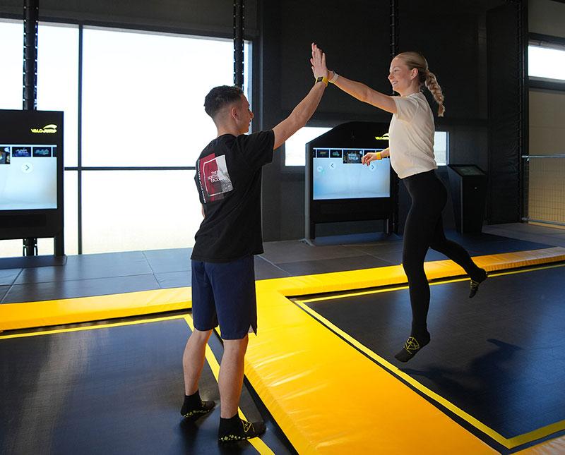 Zwei Jugendliche geben sich auf einem Trampolin im CUBE ein High Five