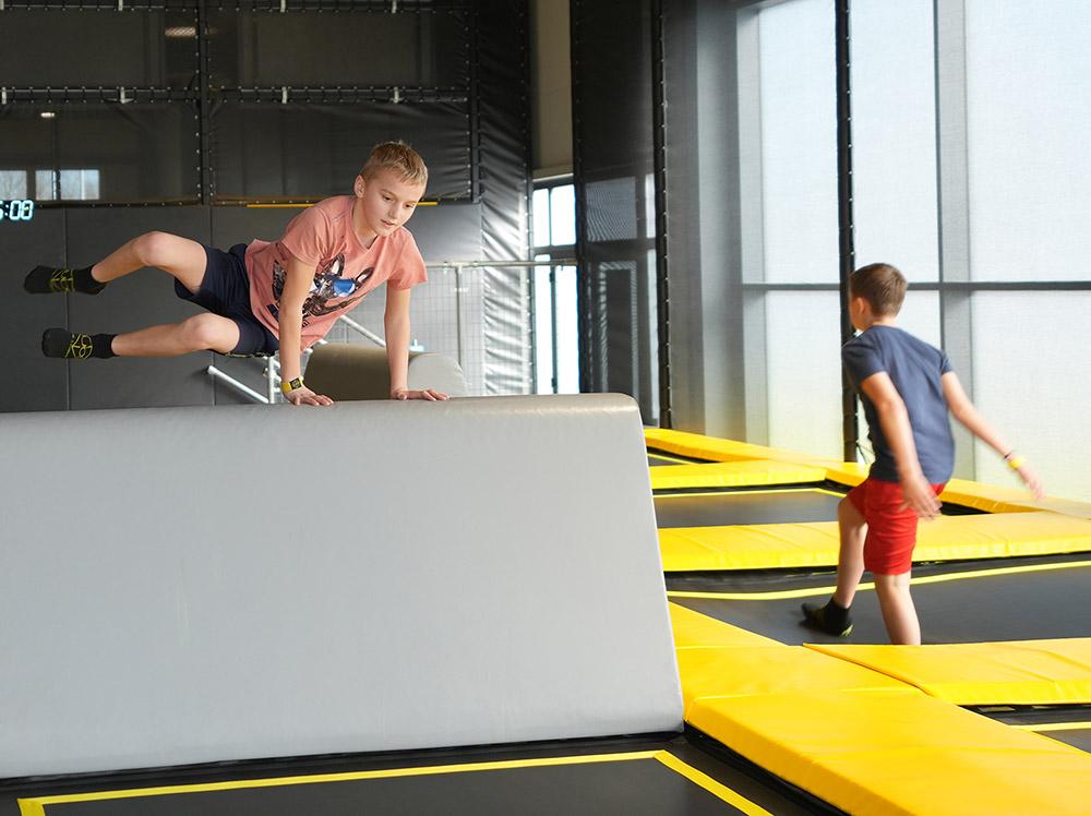 Zwei Kinder bewegen sich an den gepolsterten Trampolinhindernissen